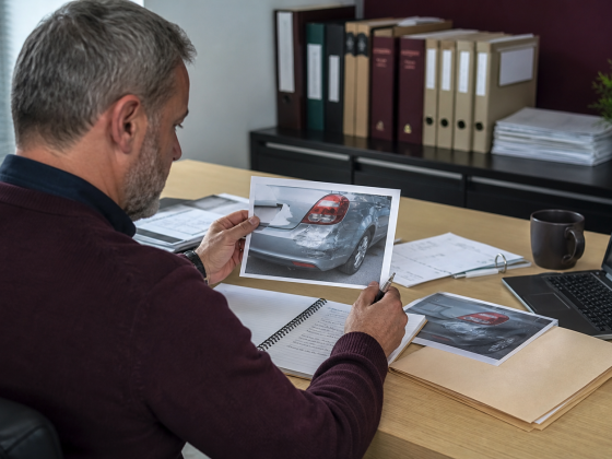 Aviva Uses AI to Challenge a New Generation of Insurance Fraud 1 Insurance investigator comparing a vehicle claim photograph with structured evidence on a desk